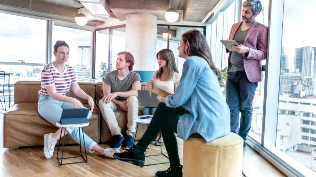 Obrazek przedstawia siedzących i rozmawiających ze sobą ludzi